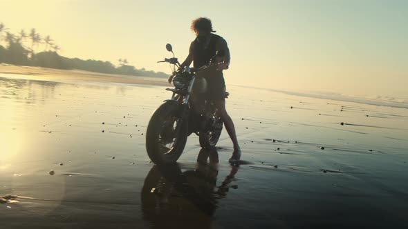 Man Kickstarting Light Bike at the Ocean Beach