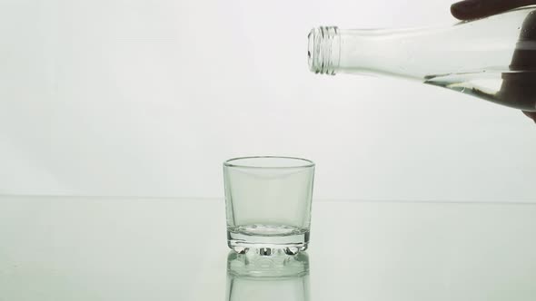 Сrystal Clear Water or Vodka Pouring From a Bottle Into a Shot