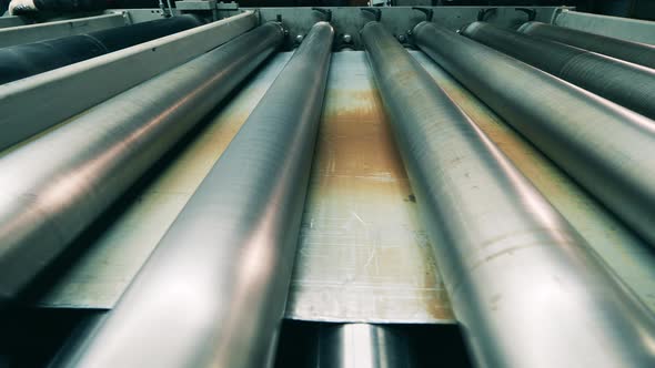 Metal Sheet Is Moving Under a Rolling Conveyor