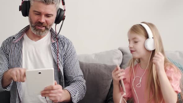 Little Girl Listening Music in Headphones with Grandfather