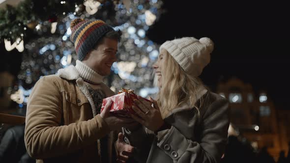 A Handsome Man Presenting a Gift to Her Girlfriend at Xmas Night at Old Town Square