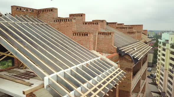 Aerial view of unfinished brick apartment building with wooden roof structure under construction.