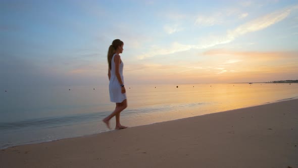 Young Woman Walking Alone on Sandy Beach By Seaside Enjoying Warm Tropical Evening