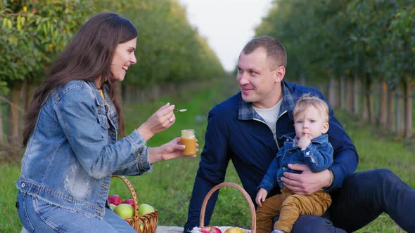 Children Food Mother Feeds Little Son with Spoon with Fruit Puree in a Jar While Sitting in His