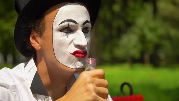 Mime in a Black Hat Drinks Alcohol Outdoors. Bad Habits