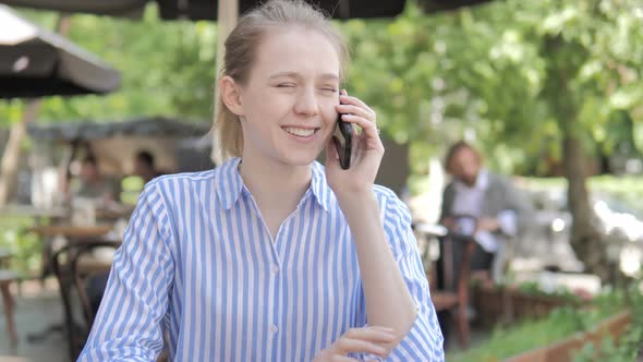 Young Woman Talking on Phone, Sitting in Cafe Terrace