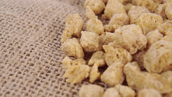 Textured dehydrated organic soybean flakes on a rustic burlap. Macro