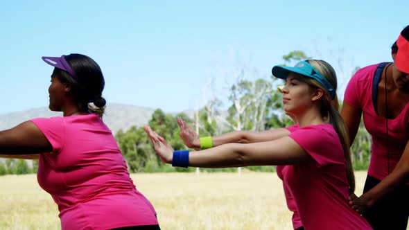 Female trainer assisting women while exercising in the boot camp