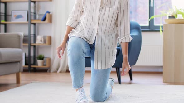 Young Woman Unfolding Carpet at Home