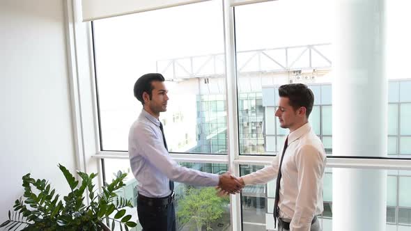 slow motion two young businessman indoor office interior shaking hands