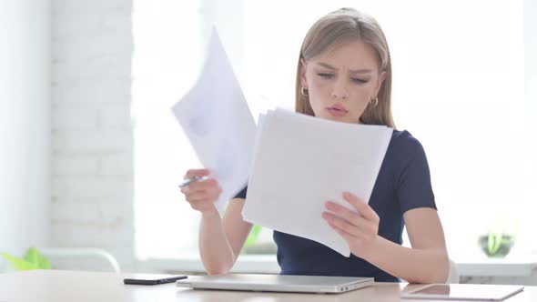 Woman Upset While Reading Documents in Office