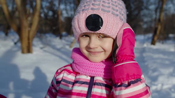 Smiling Shy Child Kid Looking at Camera Fooling Around Making Faces in Winter Snowy Park Forest