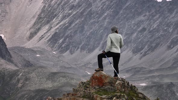 A Young Attractive Caucasian Caucasian Woman in Trekking Clothes with Trekking Sticks Stands on Top