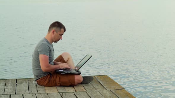 Full side view of smiling mature man using laptop on pier