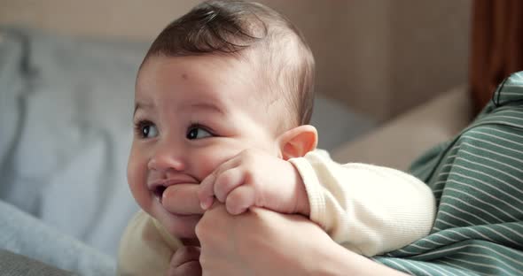 a Young Mother is Holding a Beautiful Sevenmonthold Son Who Smiles and Gnaws at Fingers and Mother's