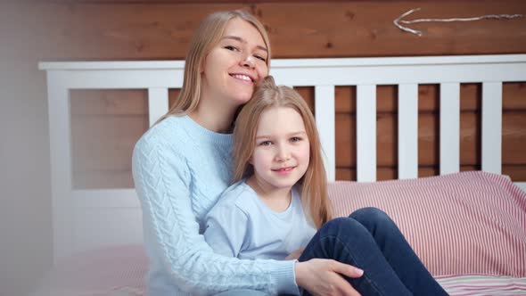 Medium Shot Portrait of Happy Mother Hugging Her Little Daughter Looking at Camera