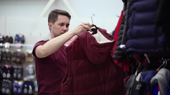 Man is Talking Waistcoat From Hanger in Hall of Clothing Shop