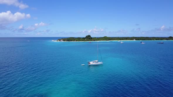 Wide birds eye travel shot of a white sand paradise beach and aqua blue ocean background in colourfu