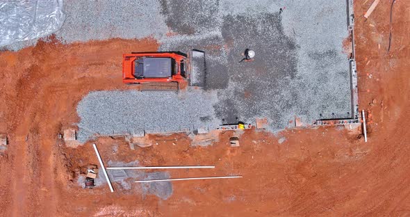 On a Construction Site a Bucket From an Excavator is Leveling Gravel at the Foundation of a Building