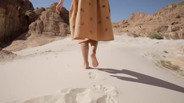 Lonely Woman Legs Go Along the Desert Barefoot on the Sand Leaving Footprints Close-up. Girl in