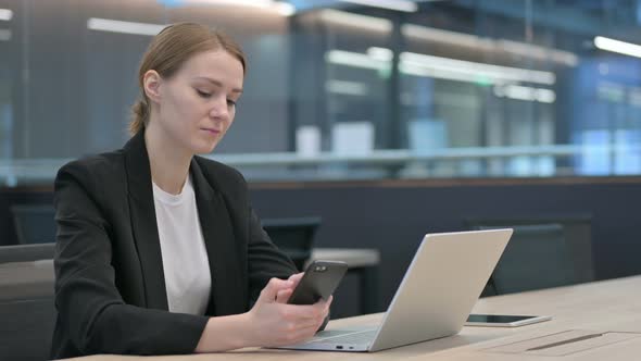 Businesswoman Working on Smartphone and Laptop in Office