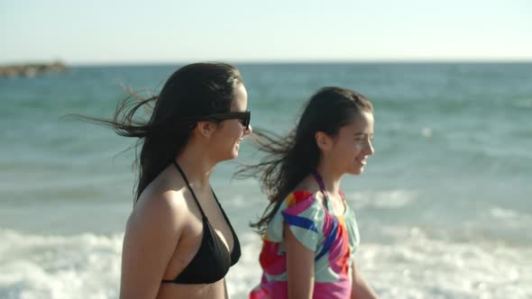 Side View of Smiling Teenage Girls Walking Along Coastline