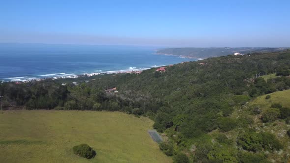 Drone shot of Wilderness hills in South Africa - drone is flying over some farms towards the beach a