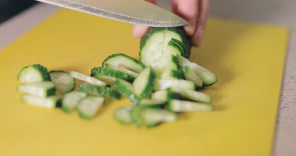 Closeup Hands Cut Cucumber on a Board