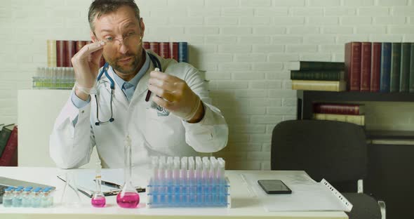 Dolly Shot of a Doctor with a Blood Sample in a Test Tube  He Writes a Report in the Laboratory