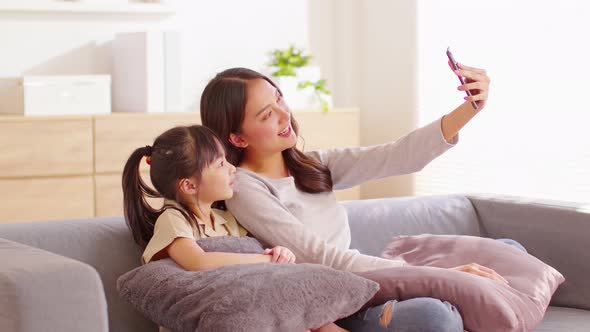 Asian young mother and her daughter have video call conference with family having fun together