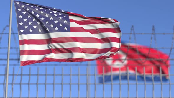 Waving Flags of the USA and North Korea Separated By Barbed Wire