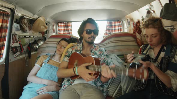 Friends Playing Guitar and Photographing in Van during Road Trip