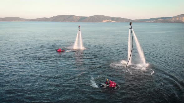 Adventurous People Hovering with Jet Packs Over Water