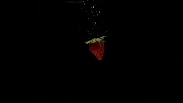 Slow Motion One Strawberry Falling Into Transparent Water on Black Background