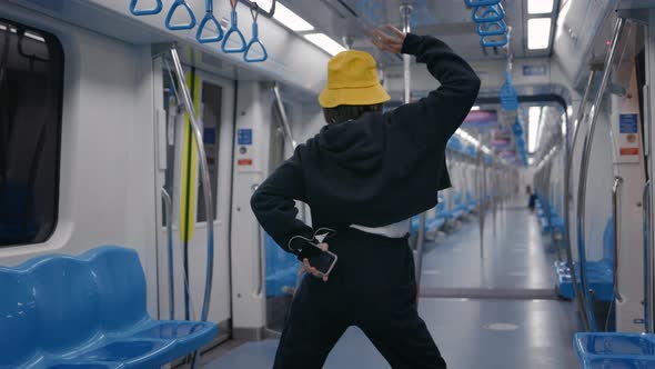 Woman Using Mobile and Earphones While Dancing at Metro