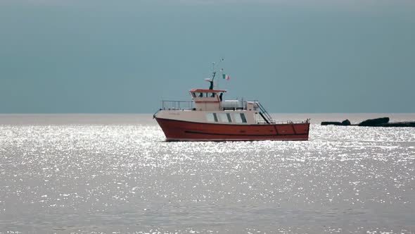 Sunbeams Reflects on the Ripple Water While Ship with Red Bottom Floats Ocean