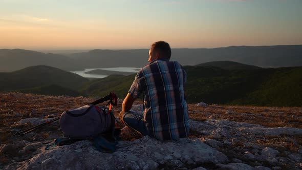 Adult Man Rest Sit on Mountain Hike Travel Rock and Enjoy Sunset View