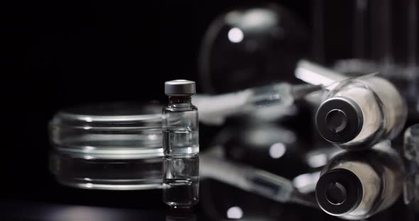 Laboratory Equipement: Syringe and Medicine, Test Tubes and Flasks Rotating on Black Background