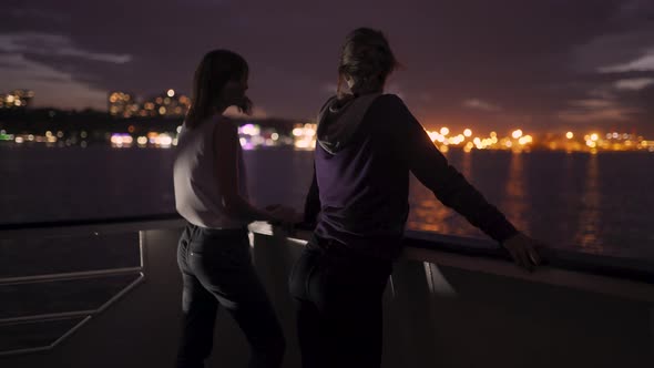 Silhouette of Two Attractive Young Women Traveling on a Ship at Night