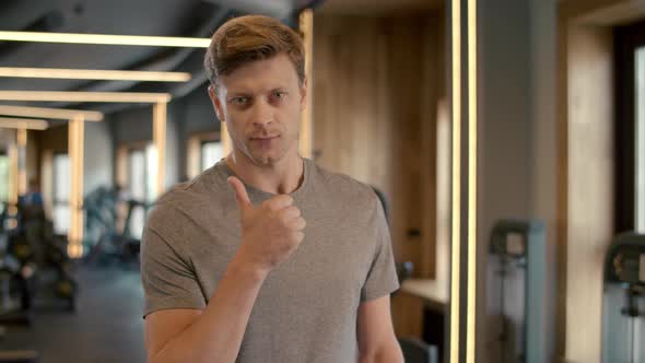 Handsome Fitnessman Showing Thumb Up in Sport Club. Sportsman Standing at Gym.