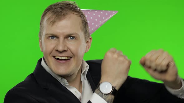 Drunk Disheveled Young Businessman in Festive Cap Celebrates and Dances