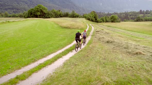 Aerial view of two cyclists riding bike in the forest on dirt road at Slovenia.