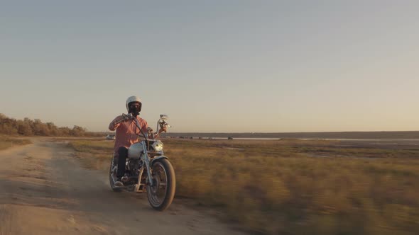 Motorcyclist Driving His Motorbike on the Dirt Road During Sunset  Shot