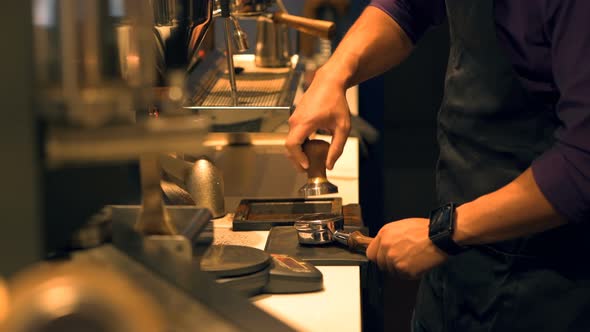 Barista pressing ground coffee into portafilter by tamper to making coffee 4k