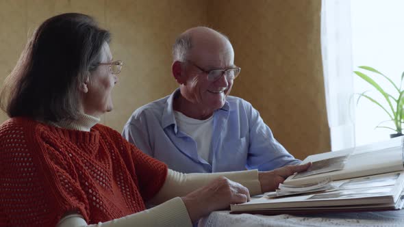 Elderly Couple in Love Enjoy Moments of Family Life Looking Through Old Photos From a Photo Album