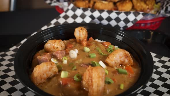 Bowl of traditional shimp sausage cajun etouffee topped with green onions, slider 4K