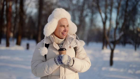 Portrait of a Homosexual Man Walking in a Winter City Park in Warm Clothes with a Disposable Cup of