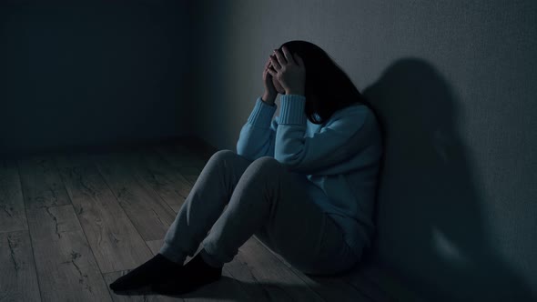 Woman Sits on Floor Leaning on Wall Feeling Upset By Quarrel