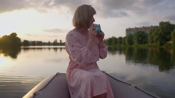 Creative Talented Trans Woman Taking Photos of Nature Sitting in Boat on Summer Lake at Sunset