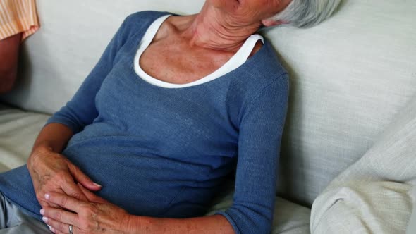 Senior woman sleeping on sofa in living room